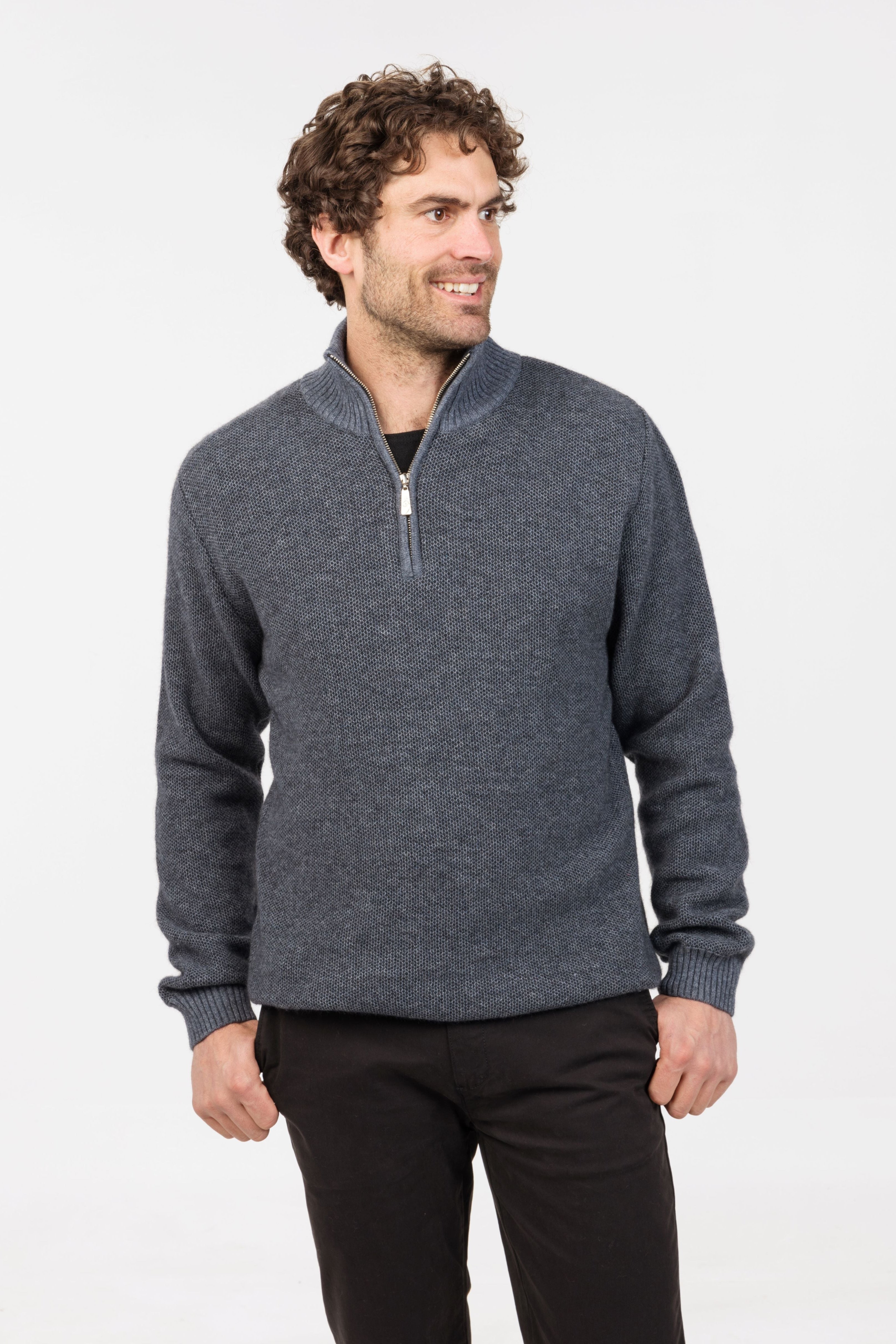 A man wearing a Native World gray half zip textured sweater made from a blend of possum merino wool, paired with black pants.